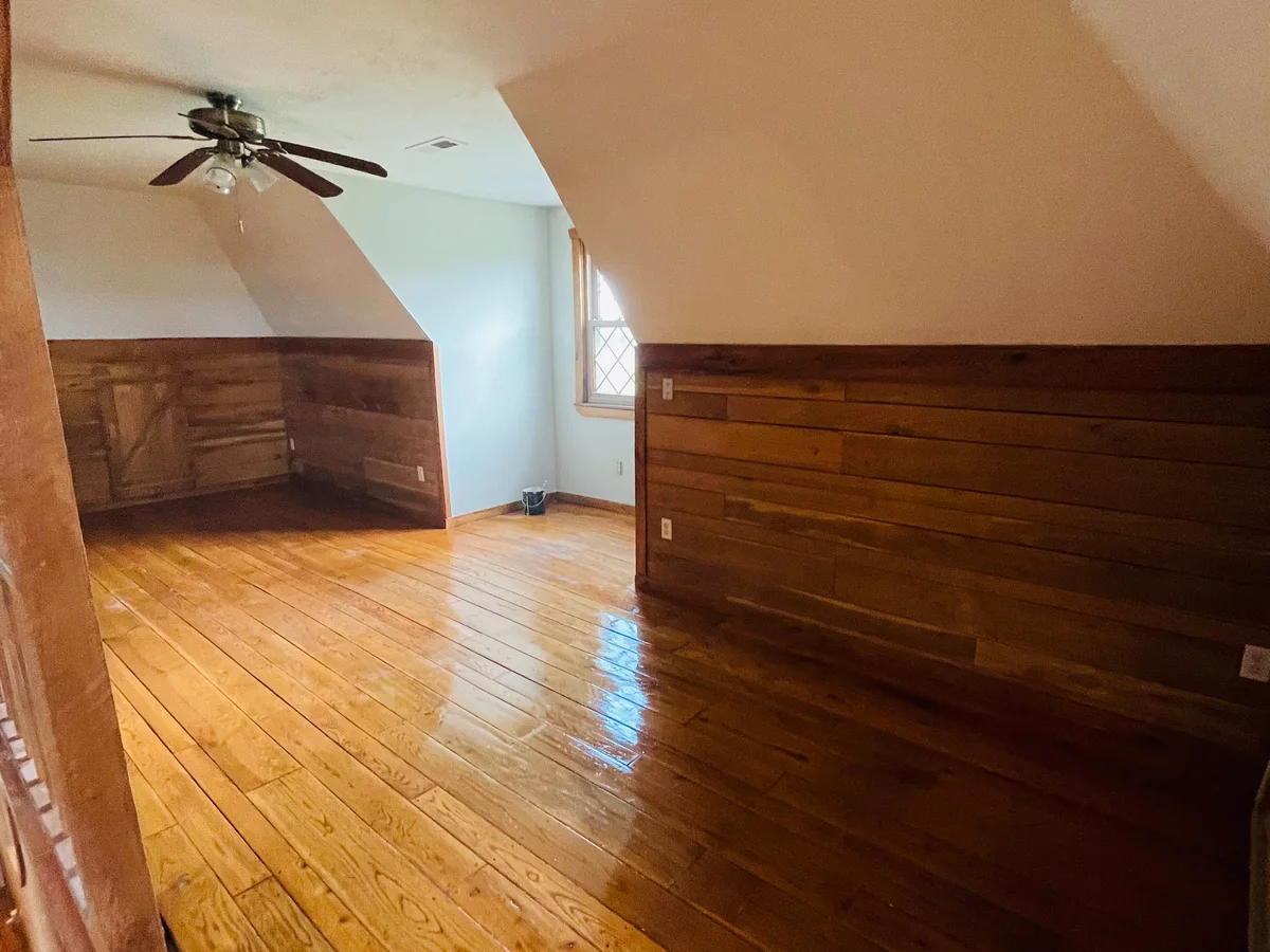 Attic room with wood floor and painted walls